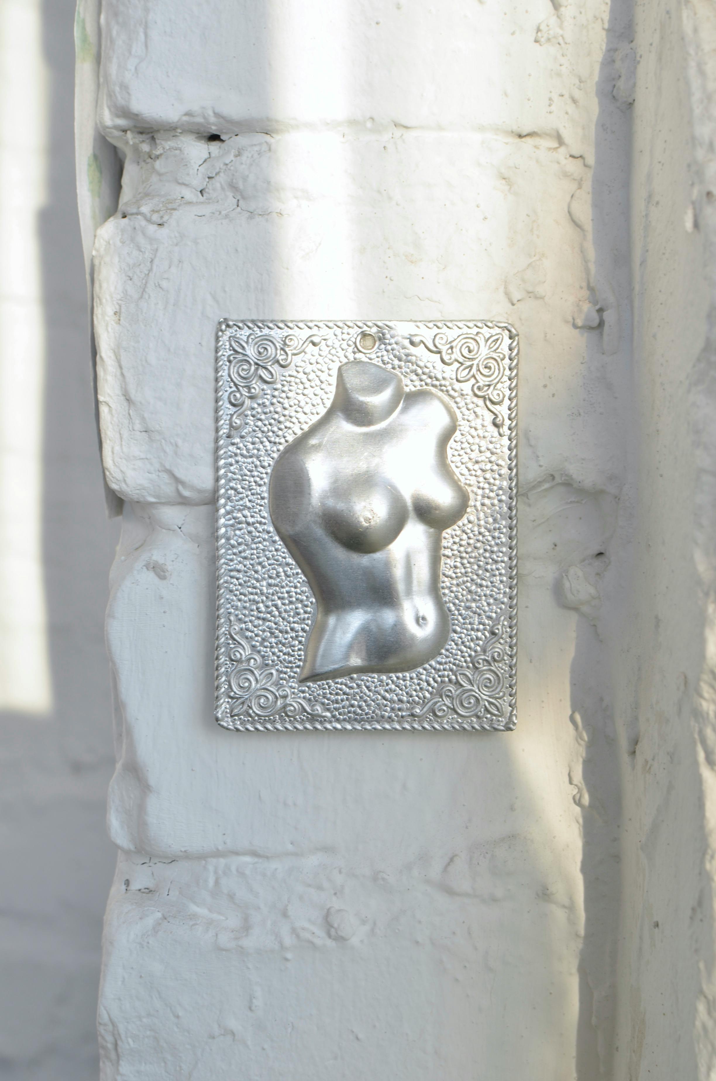 engraving representing nude female torso on rough wall