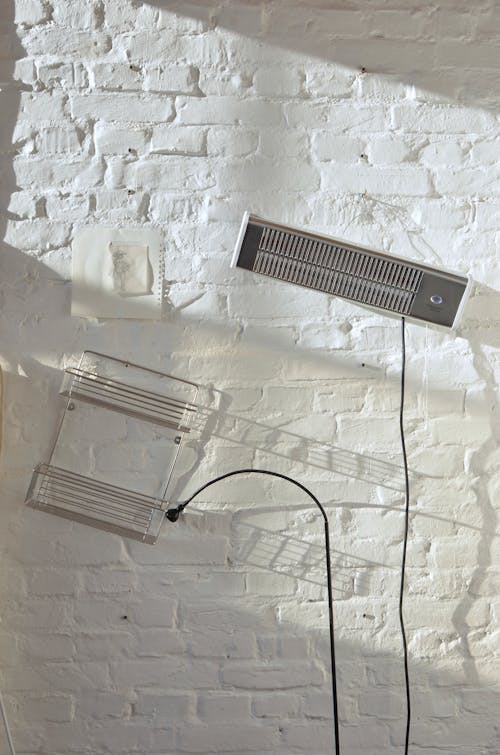 Free Lamp with long wire hanging near metal shelves on rough white brick wall on sunny day in house Stock Photo