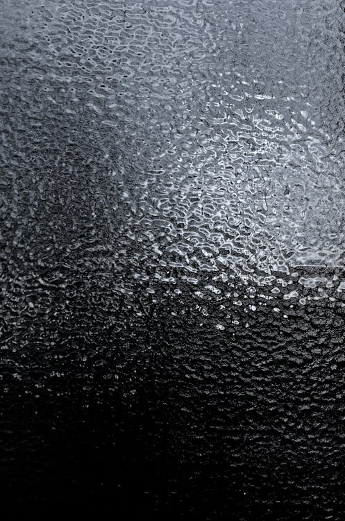 Full frame background of glass texture with uneven smooth surface with reflection in daylight