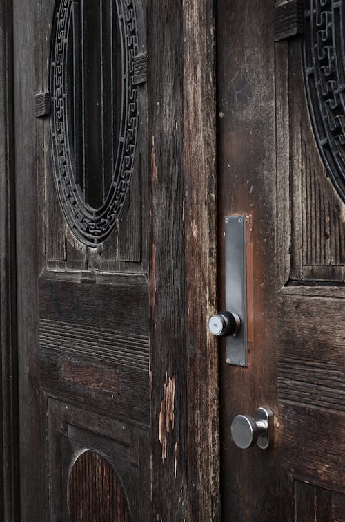 Closed old fashioned doors made of brown wood with damaged surface and metal handles