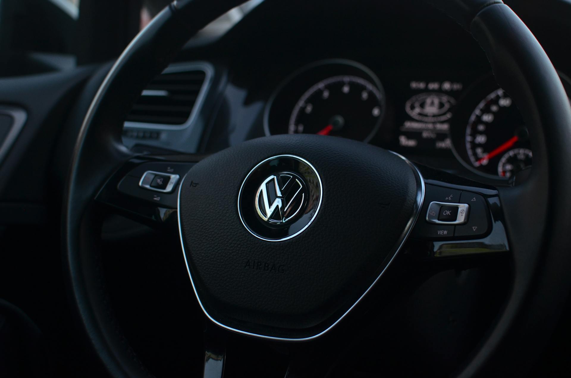 Interior of modern automobile with buttons on steering wheel with panel containing instruments and controls