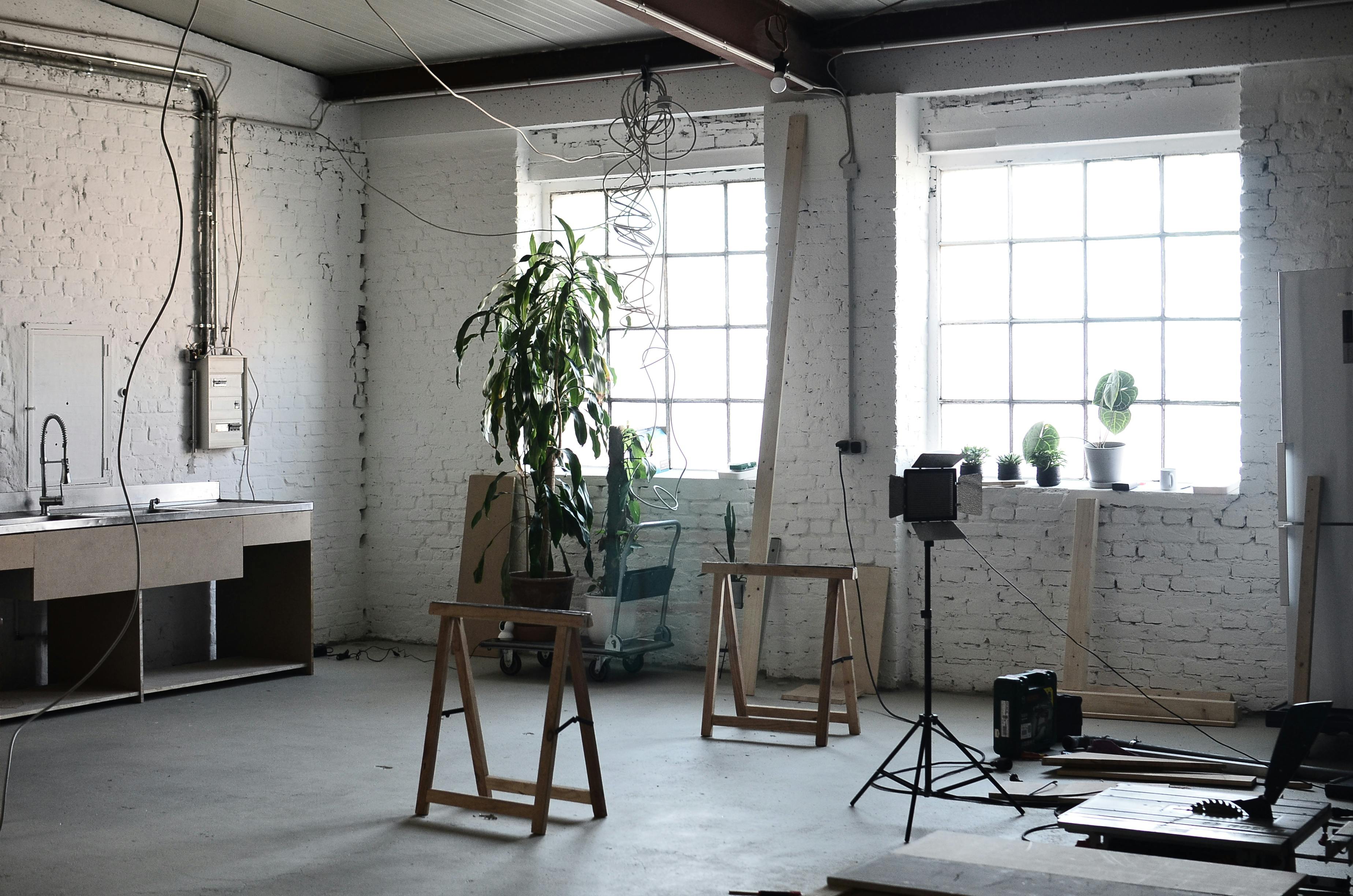 Free Interior of loft with brick wall with wires hanging on ceiling and tools for renovation  works Stock Photo