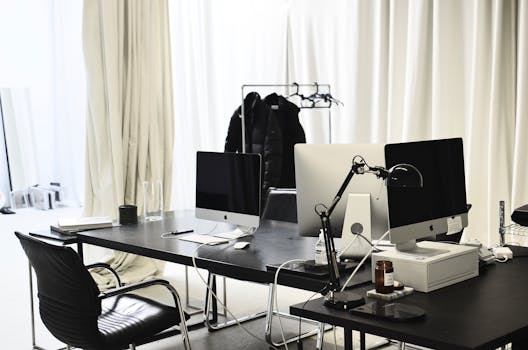 Contemporary office setup featuring computers on a black desk with elegant design and copy space.