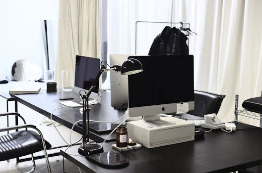 Computers with wires placed on black tables in modern convenient workspace of office