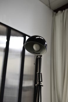 Modern black steel shimmering lamp placed in interior of convenient gray contemporary office