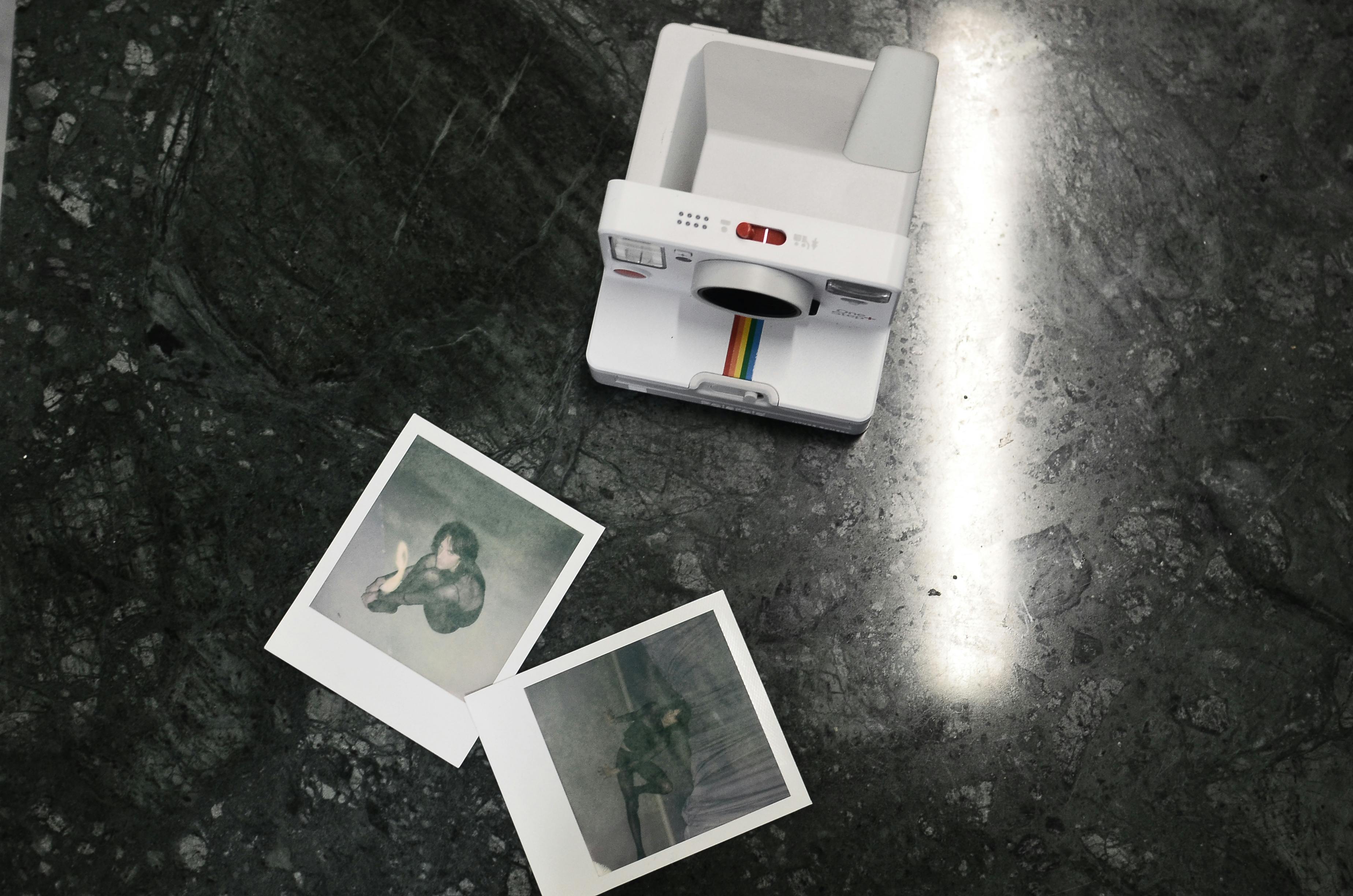 modern instant photo camera and photos placed on marble surface