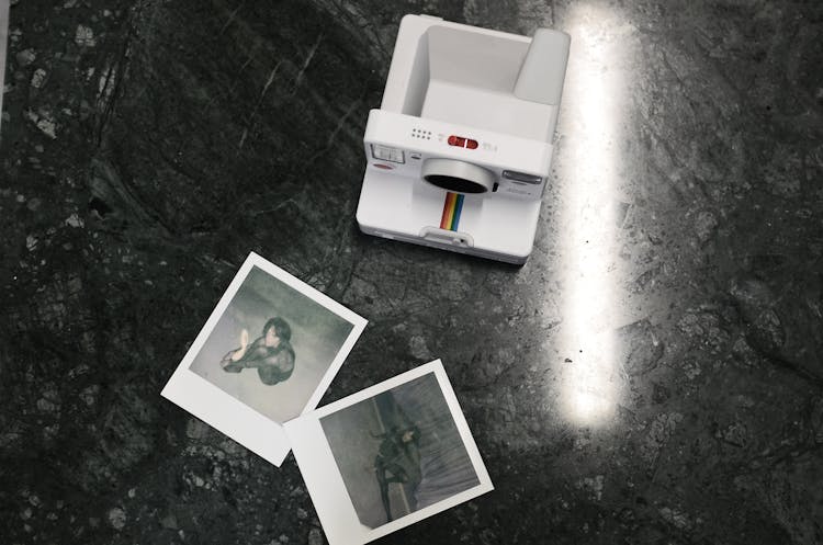 Modern Instant Photo Camera And Photos Placed On Marble Surface