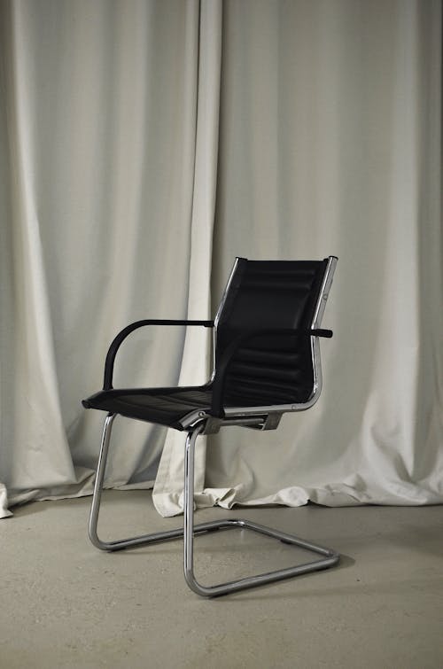 Black chair placed near light curtains