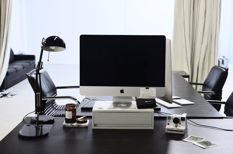 Modern Computer And Instant Photo Camera Placed On Table In Workplace