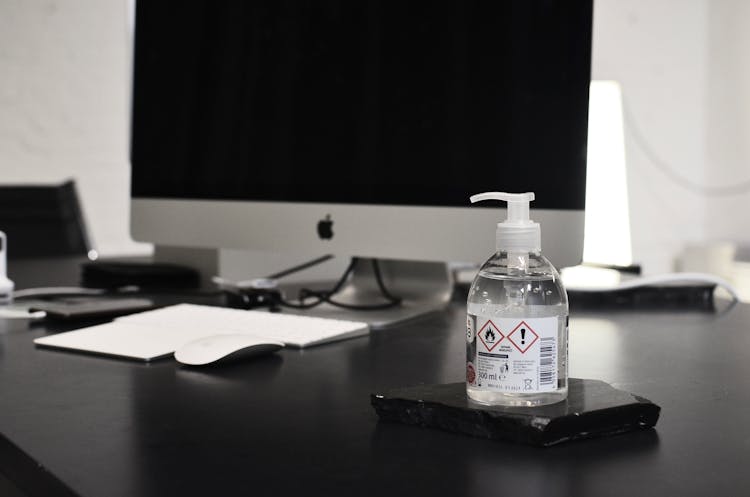 Bottle Of Antibacterial Gel Placed Near Computer At Workplace