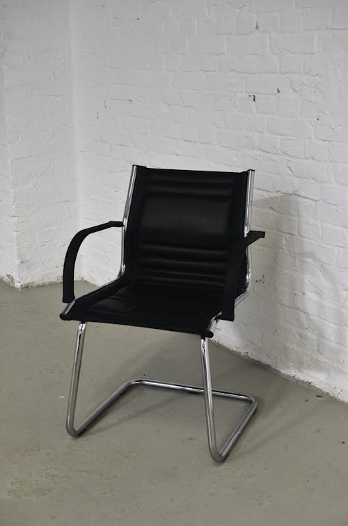Free Chair with black seat placed against brick wall Stock Photo
