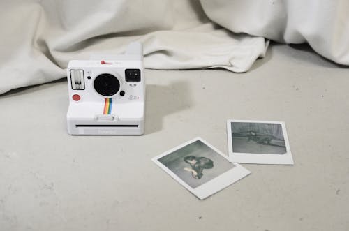 Modern instant photo camera and photos placed on floor