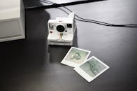 Modern instant camera with photos on table