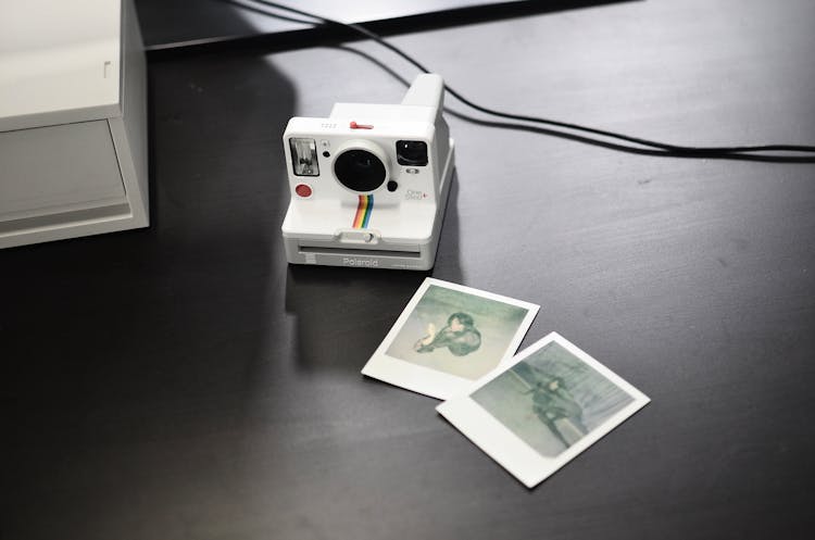 Modern Instant Camera With Photos On Table