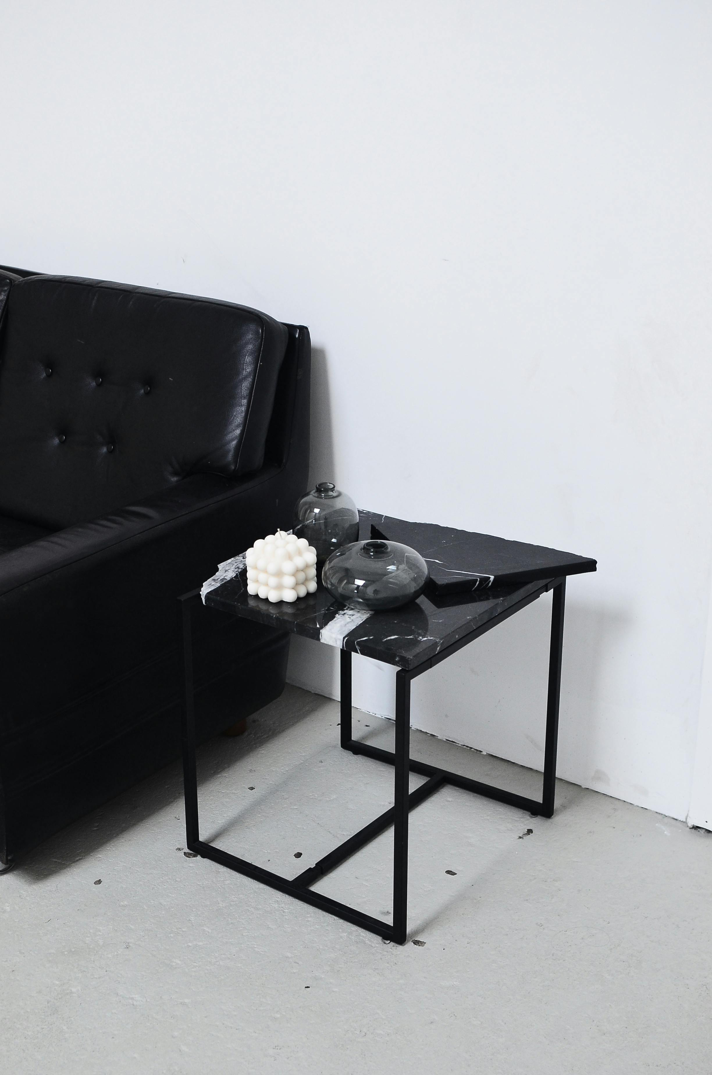 Free Modern living room corner with black leather sofa and geometric table featuring decor elements. Stock Photo