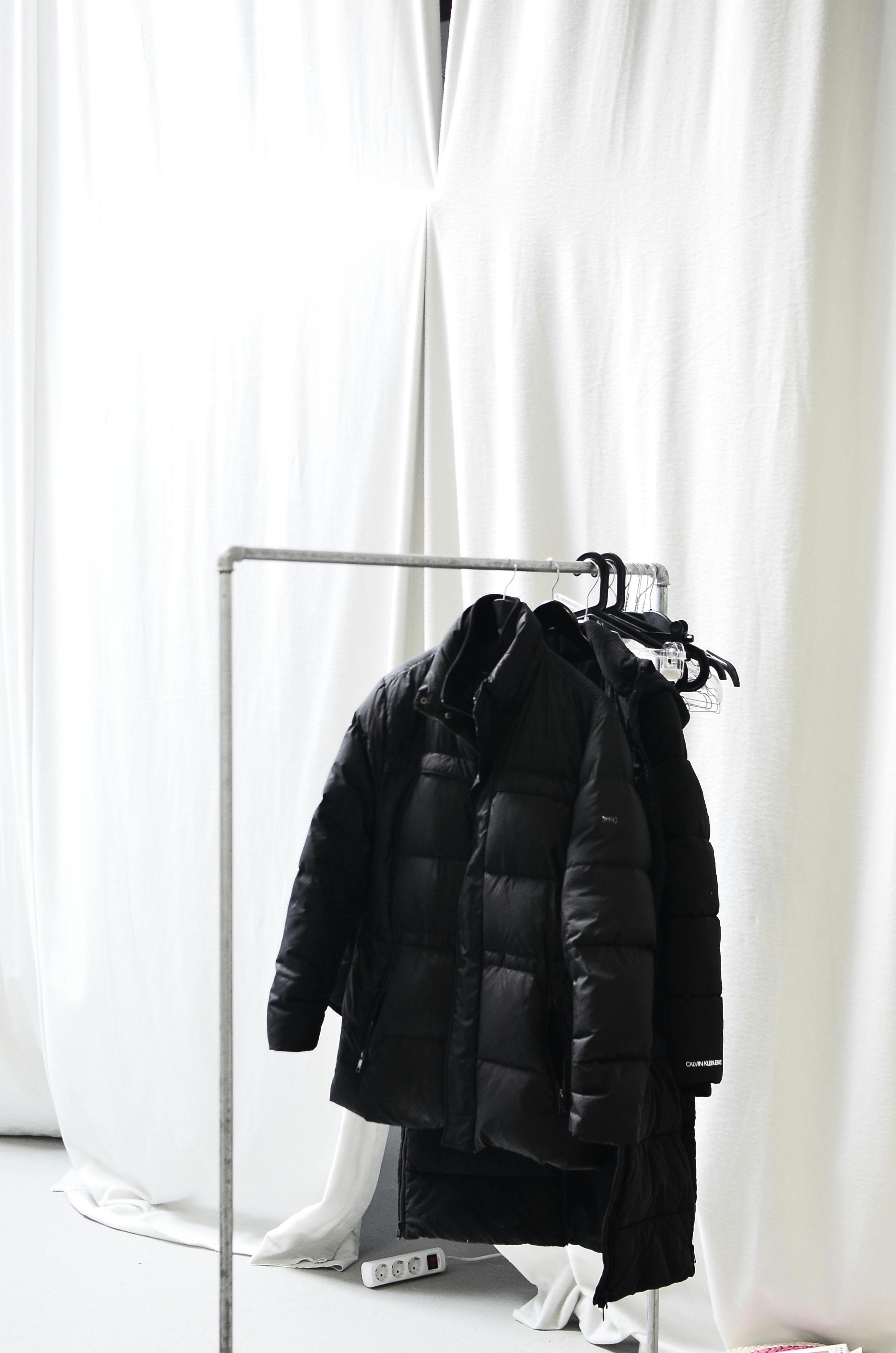 rack with outerwear against curtains in light room