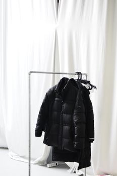 Rack with outerwear against curtains in light room