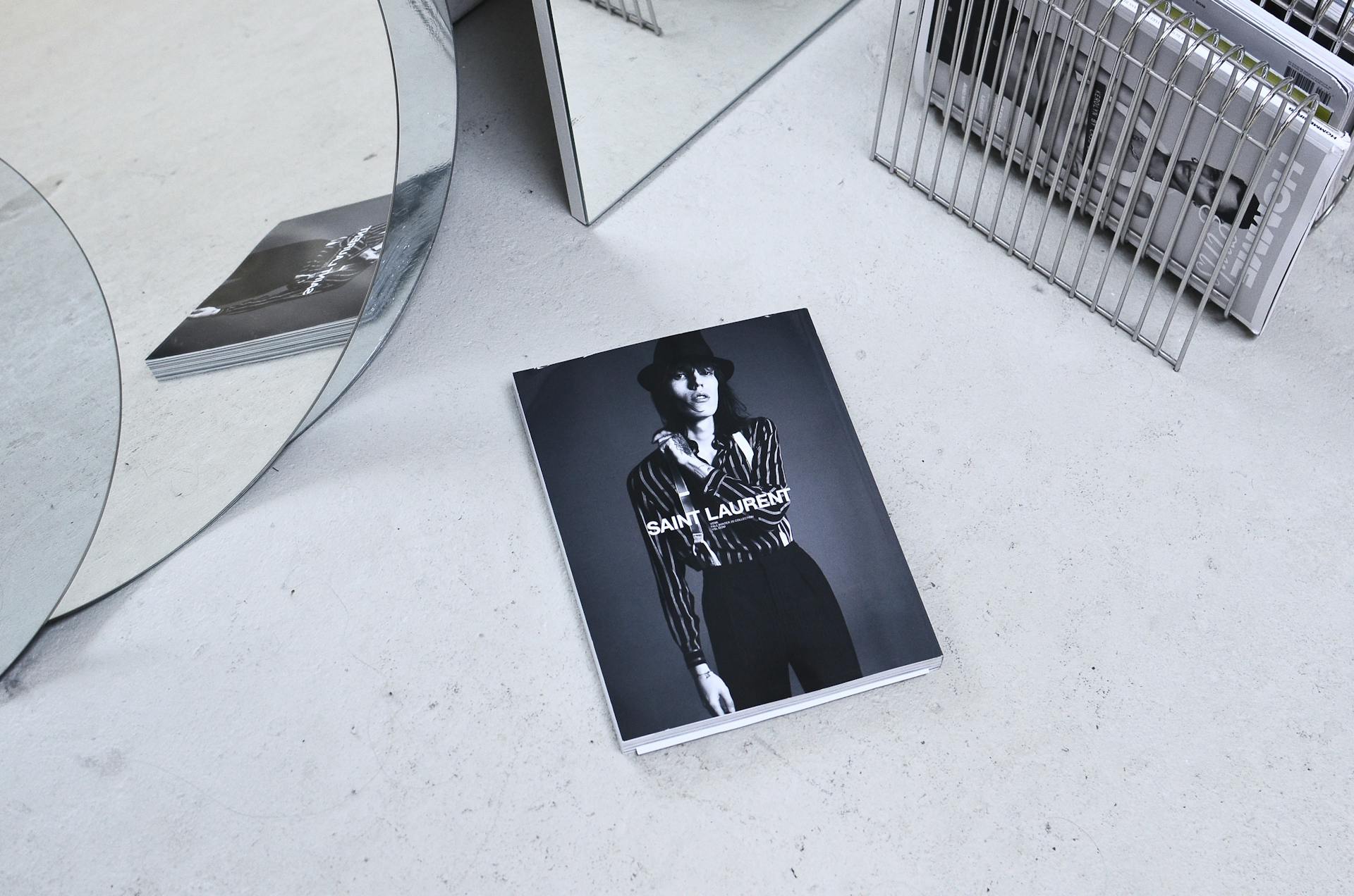 Black and white high angle fashion magazine placed on table and reflecting in geometrical mirror and rack with journals