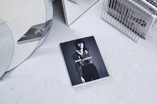 Black and white high angle fashion magazine placed on table and reflecting in geometrical mirror and rack with journals