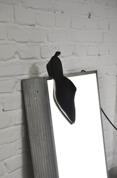 Stylish shoe hanging on bright photo lamp