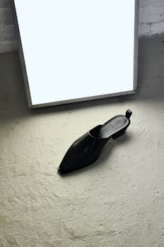Elegant black leather shoe showcased with bright lighting on a concrete floor.