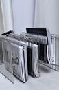 Collection of many fashion magazines on creative stand placed on floor near mirror and curtain