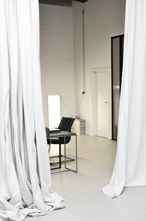 Meeting table and chair surrounded by hanging curtains · Free Stock Photo
