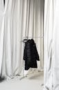 Clothes rack with warm jacket amidst hanging curtains