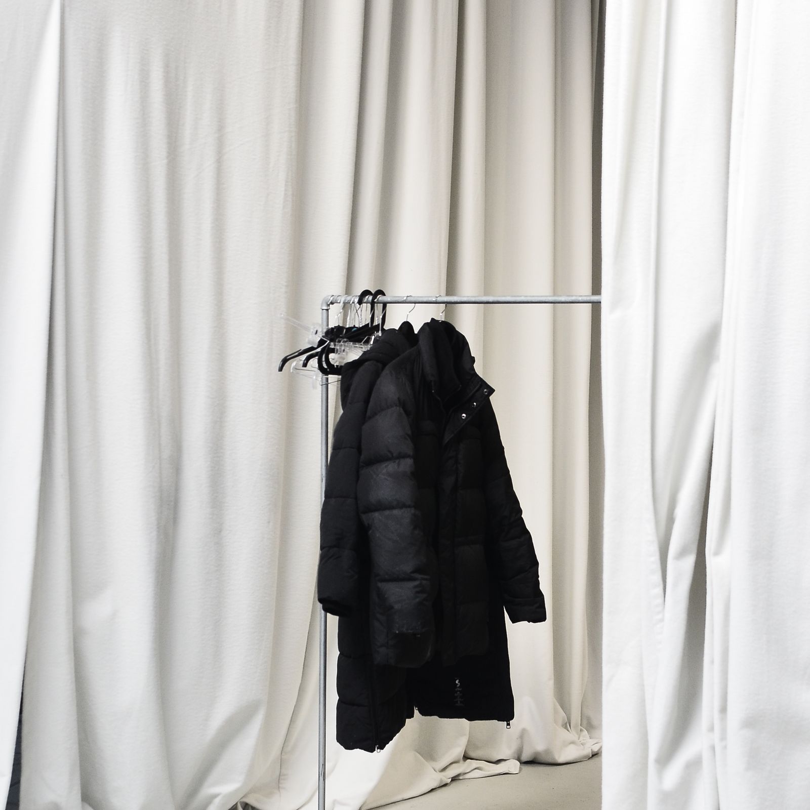 Black insulated jacket on a minimalist clothing rack
