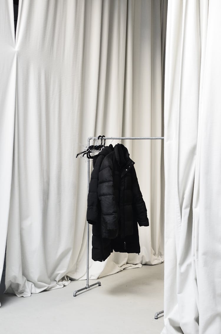 Clothes Rack With Warm Jacket Amidst Hanging Curtains