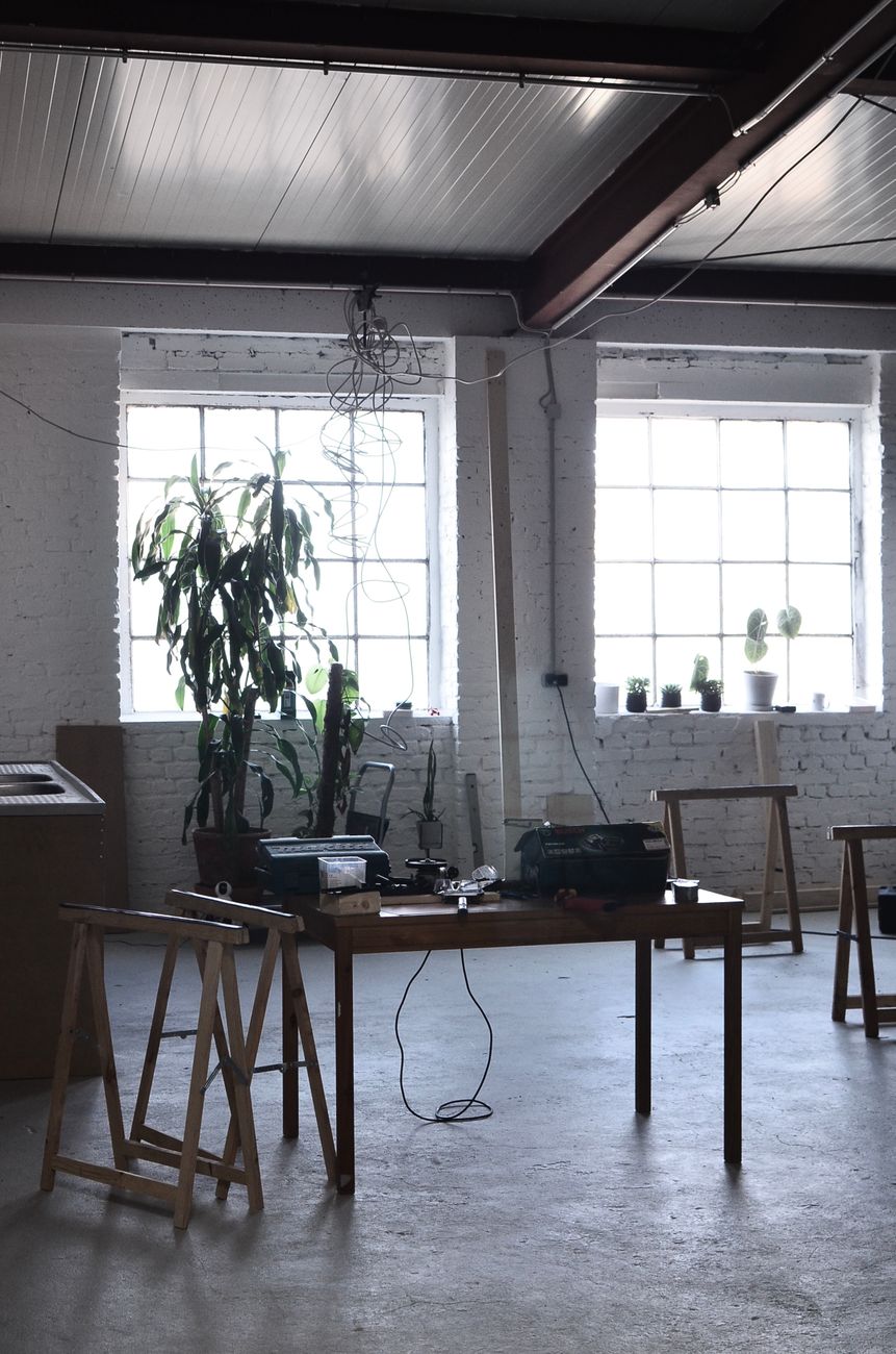 Interior design of spacious light studio with white brick walls and table in center and big green plant near window. pexels,