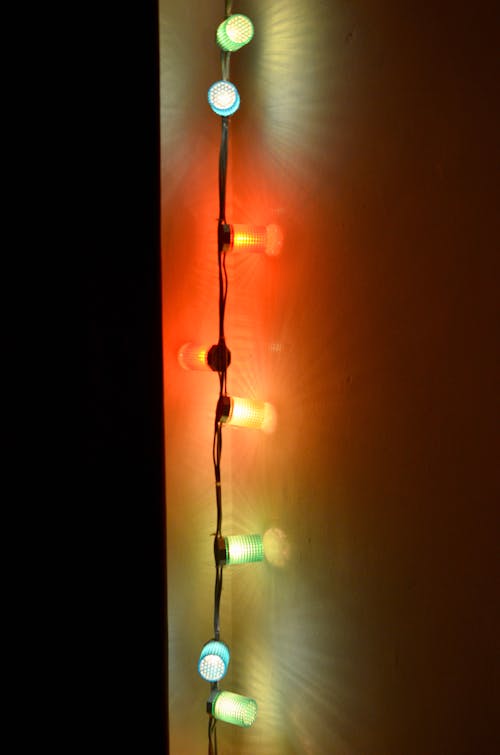 Multicolored Christmas lights with bright illumination on wall in dark room at night