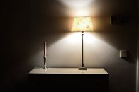 Interior of room in retro style with glowing lamp near candle in holder on shelf