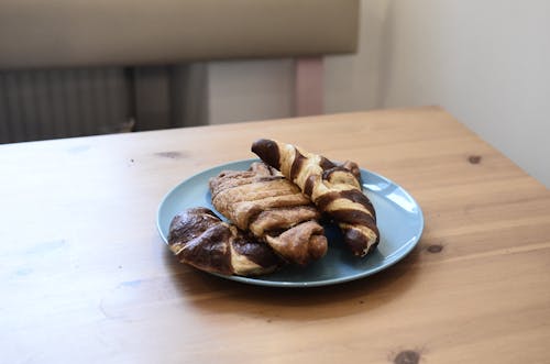 High angle of appetizing homemade croissants with milk chocolate topping on wooden table