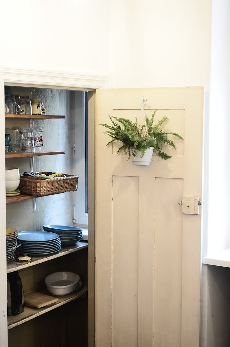 Stack Of Kitchenware On Shelves Behind Door