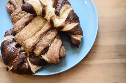 Top view of delicious crusty croissants with chocolate topping on wooden table in bakery