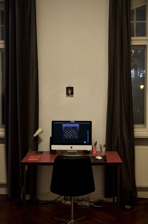 Interior of modern room with computer on table near large windows with curtains