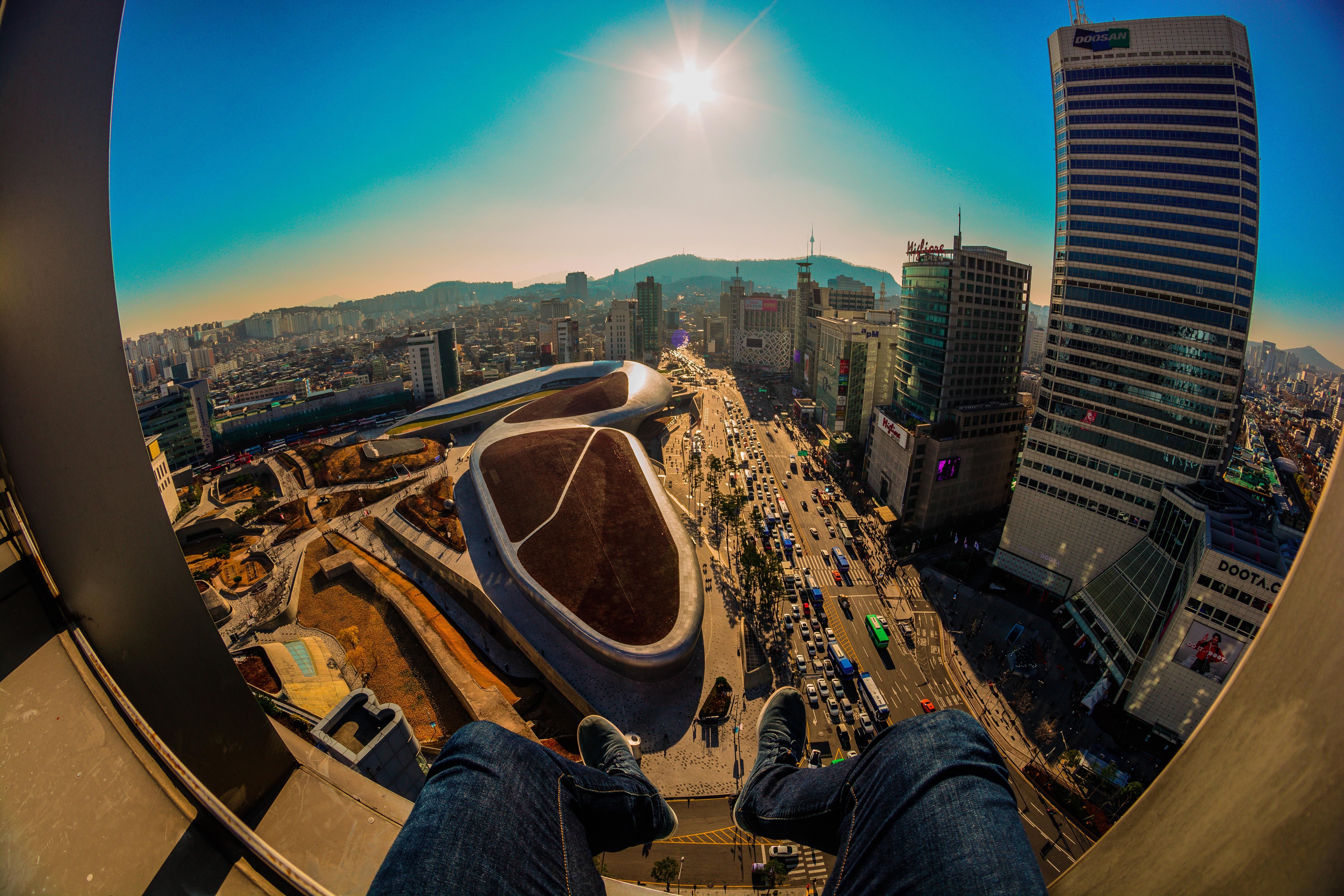 Stunning fisheye view of Dongdaemun Design Plaza and Seoul skyline under a clear sky.