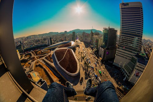 Person in Blue Denim Jeans Sitting on Top of a Building