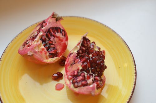 Free High angle of sweet halves of healthy pomegranate fruit on light white table Stock Photo