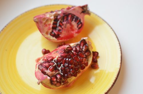Free High angle of fresh ripe pomegranate halves with seeds on yellow ceramic plate Stock Photo