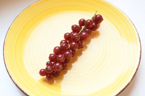 High angle of appetizing sweet berries on sprig of currant on white table