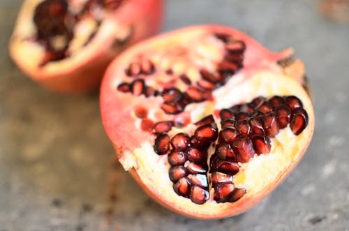 Halves of pomegranate on gray surface