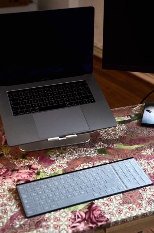 Free From above of contemporary laptop with black screen and keypad near stationary monitor placed on colorful desk in room at convenient workplace Stock Photo