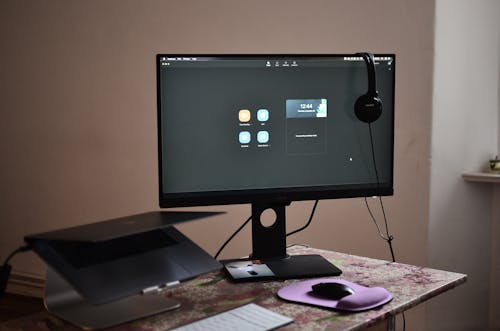 茶色の木製の机の上の黒いフラットスクリーンコンピューターモニター