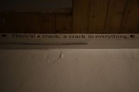 From below of phrase written on paper and nailed on white shabby wall near wooden ceiling in room in neglected house