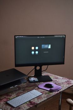 From above of contemporary stationary monitor with modern interface placed on desk with laptop white keyboard and mouse in room at convenient workplace