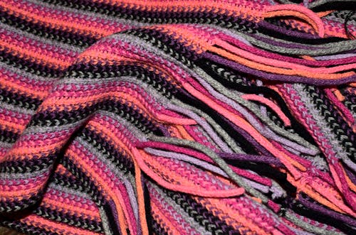 Full frame abstract background of colorful warm woolen scarf with long bright fringe