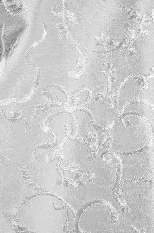 Full frame abstract background of white curtain with decorative elements sewn with shiny threads