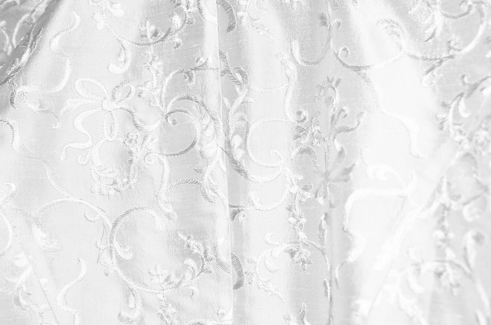 Background of white curtain with bright thick textile and creative design with ornamental elements creating swirls hanging in light room